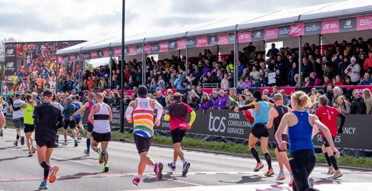 People running in front a crowd of spectators