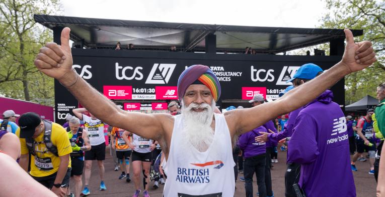 Person with arms out stretched with their thumbs up. TCS logo's in the background. 