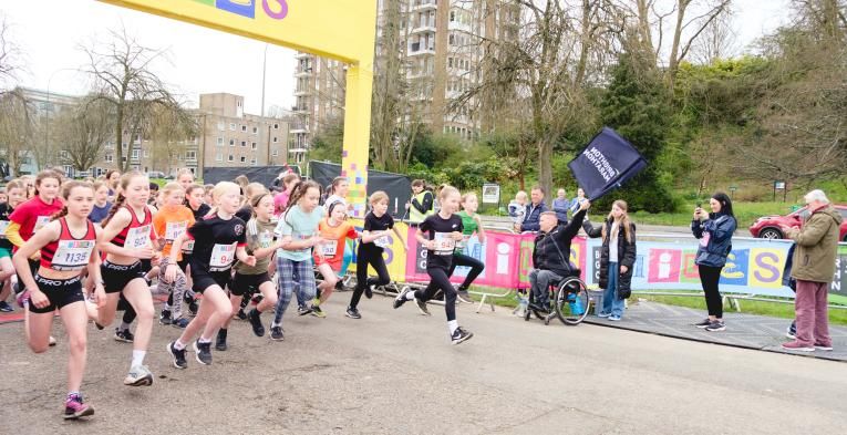 Multiple children running off the start line of the race