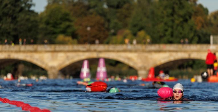 Two Swimmers swim along the swim serpentine route with a bridge in the background.