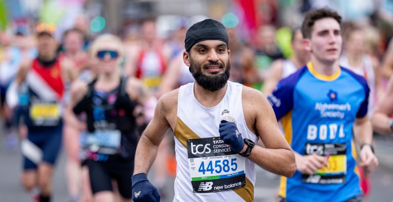 Close up of person running a race with a white and gold vest