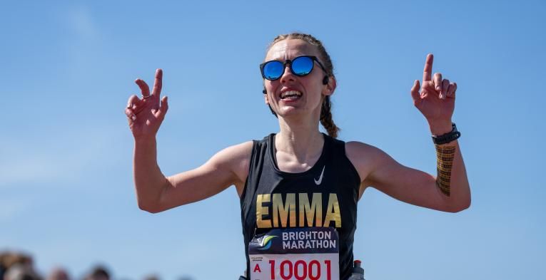 Woman holds up hands as she runs the Brighton marathon