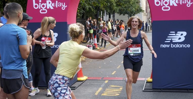 A woman crossing the finish line of the Big Relay tags in her team member to do the next leg of the race.