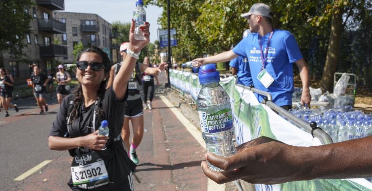 Volunteers hold out bottles of water to runners 