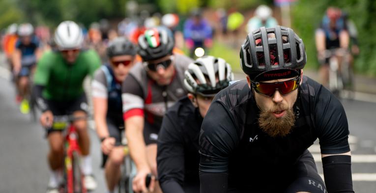 Line of cyclists cycle down road during RideLondon