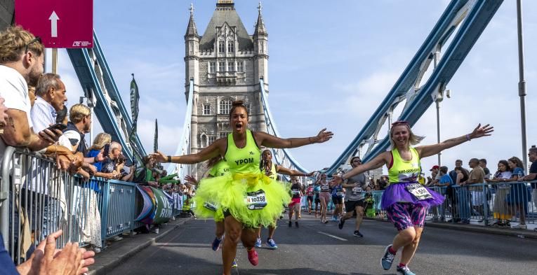 Women running across bridge in neon tutus during The Big half race