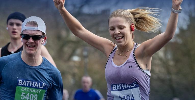 A couple of people crossing the finish line at the Bath Half marathon with smiles.