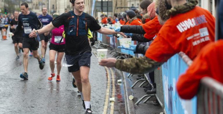 A runner gives high fives to marshals as he runs down the street.