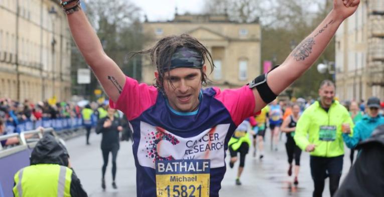 Man raising his hands as he finishes the half marathon