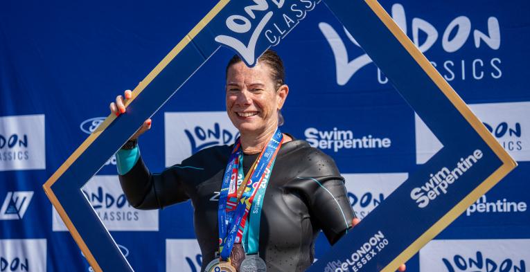 Women wearing multiple medals holding a London Classics cardboard frame in front of her