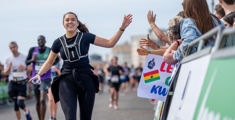 Runner high fives spectators as she heads to the Finish Line