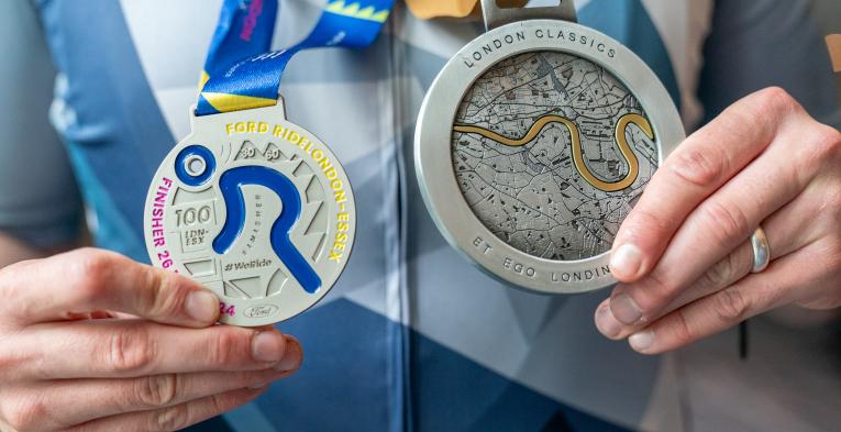 A person holding a London Classics and a RideLondon medal