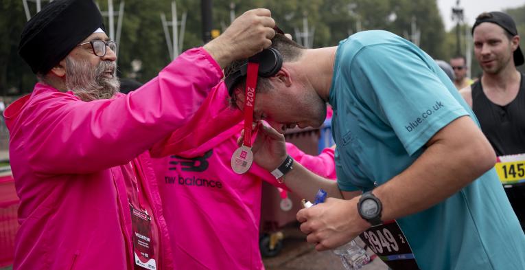 volunteer puts a finisher medal around a runners neck