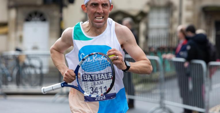 A runner dressed in fancy dress holding a tennis racket during the Bath Half