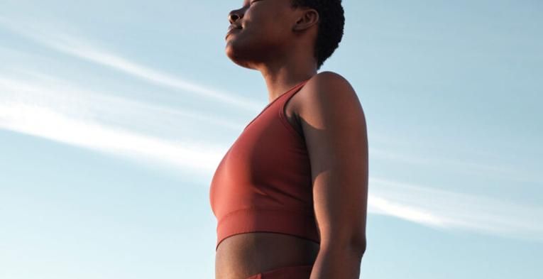 A woman embracing the sunshine in active sportswear with her eyes closed and head raised high.