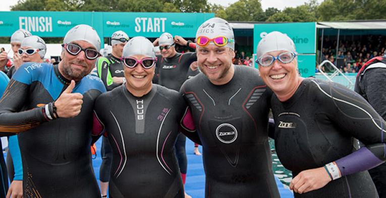 Four swimmers looking at the camera smiling.