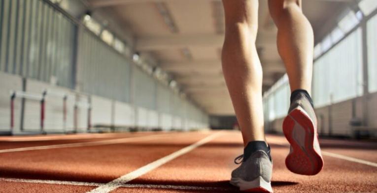 The legs of an athlete on an indoor running track in the afternoon.