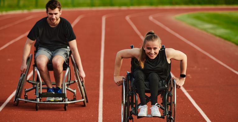 Two wheelchair users enjoying their outdoor track session