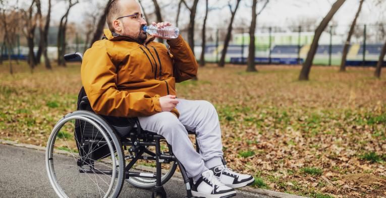 Wheelchair user stops in the park for a drink of water