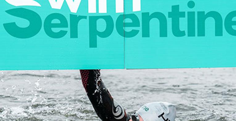 Someone swimming under a "swim serpentine" banner