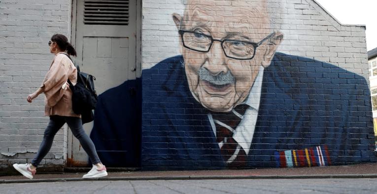 A woman walks past a new mural of British veteran and fundraiser Captain Tom Moore