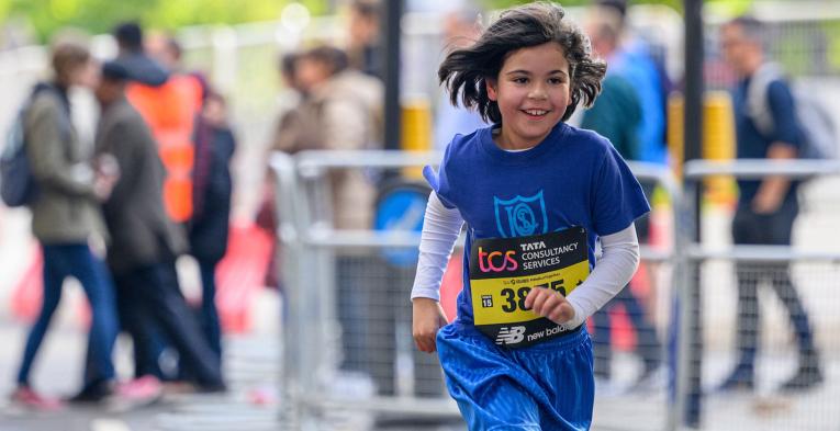 A young competitor in the race runs down The Mall during The TCS Mini London Marathon on Saturday 1st October 2022