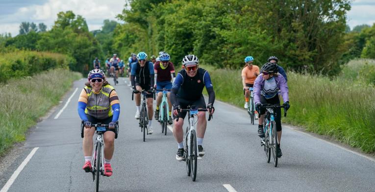 Smiling cyclists ride along a country road