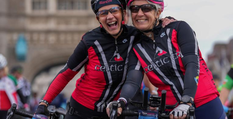 Two riders smile and hug at Tower Bridge