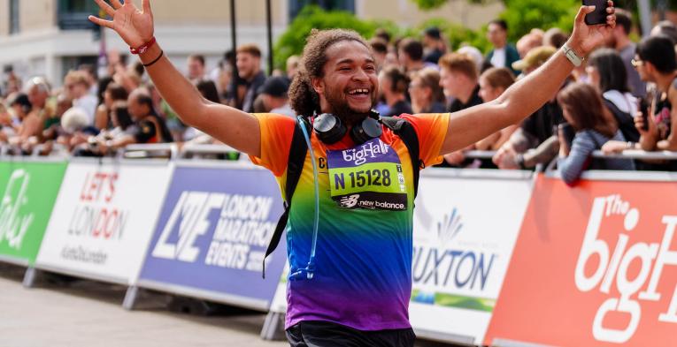 Man smiles with arms up as he runs The Big Half