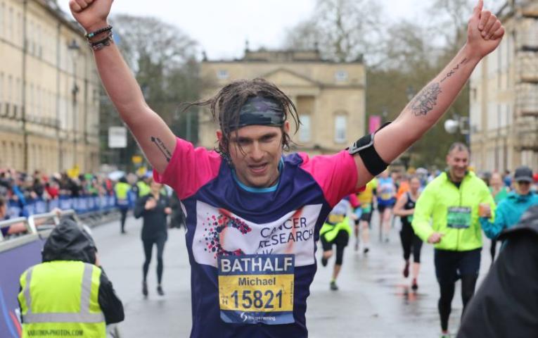 Man raising his hands as he finishes the half marathon