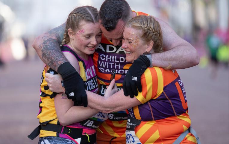 A group of runners hug on the finish line of the London Marathon