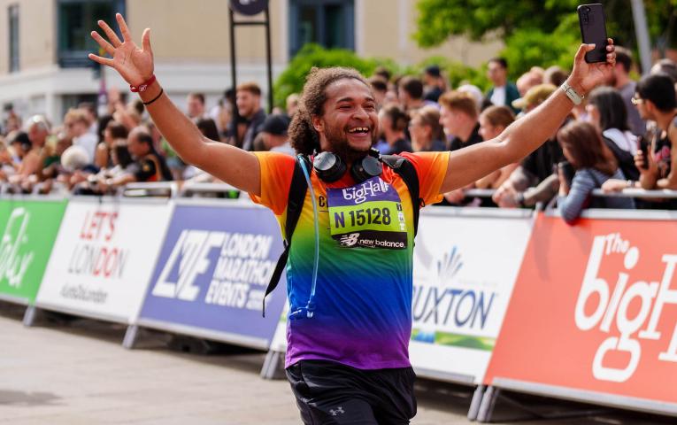 Man smiles with arms up as he runs The Big Half