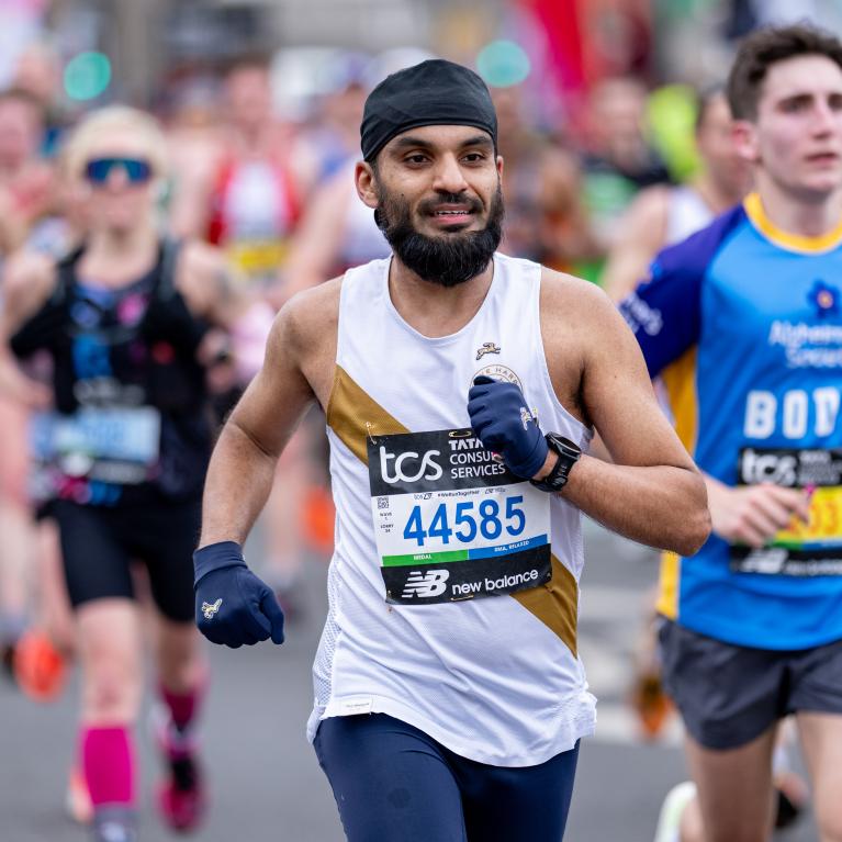 Close up of person running a race with a white and gold vest