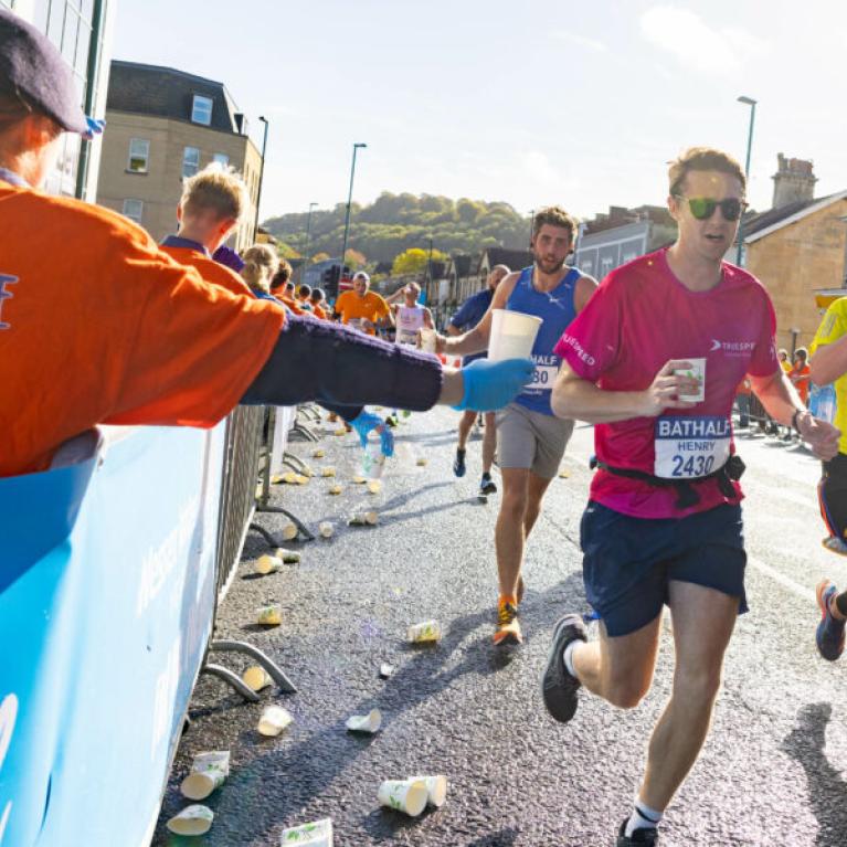 Course marshals handing out cups of water to runners.