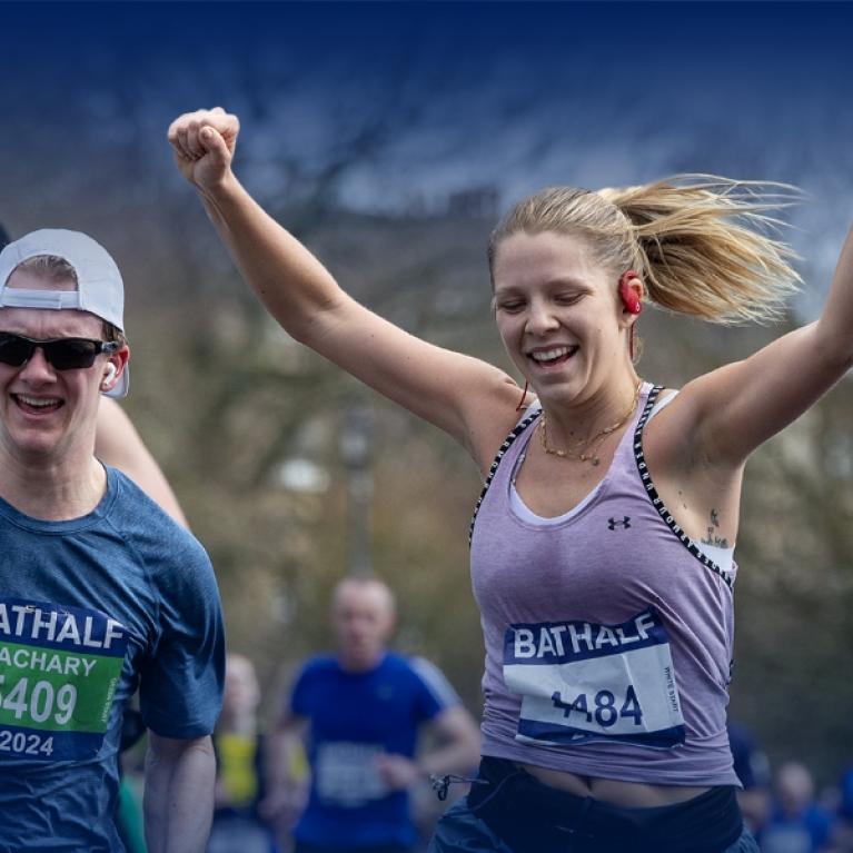 A couple of people crossing the finish line at the Bath Half marathon with smiles.