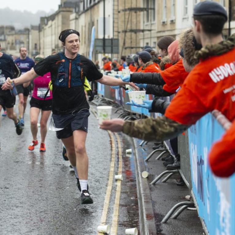 A runner gives high fives to marshals as he runs down the street.