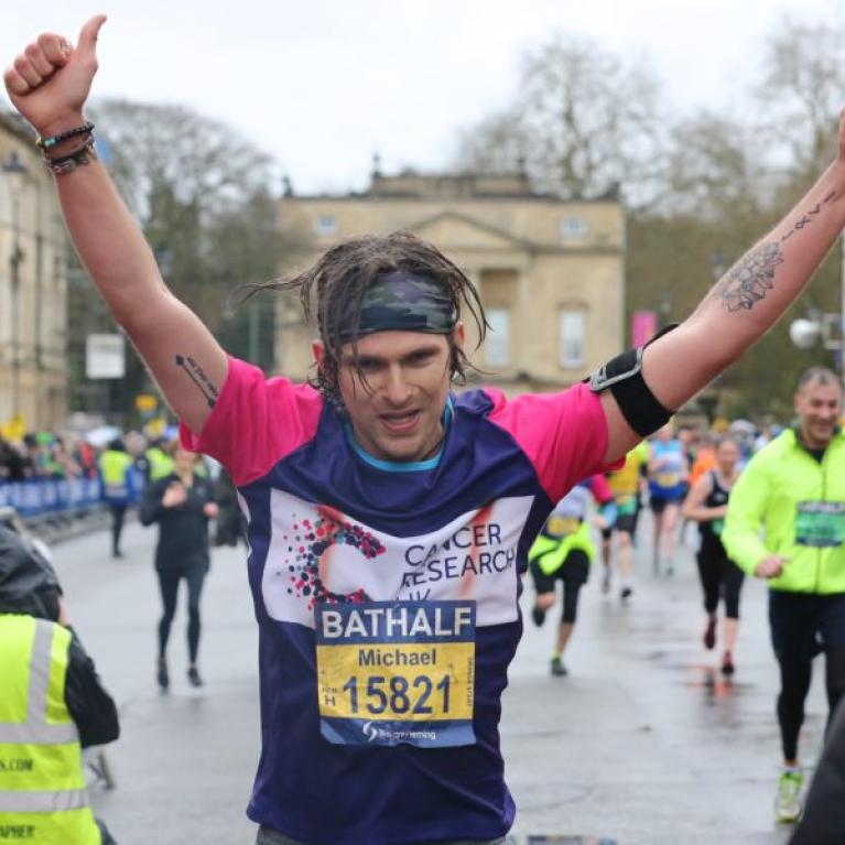 Man raising his hands as he finishes the half marathon