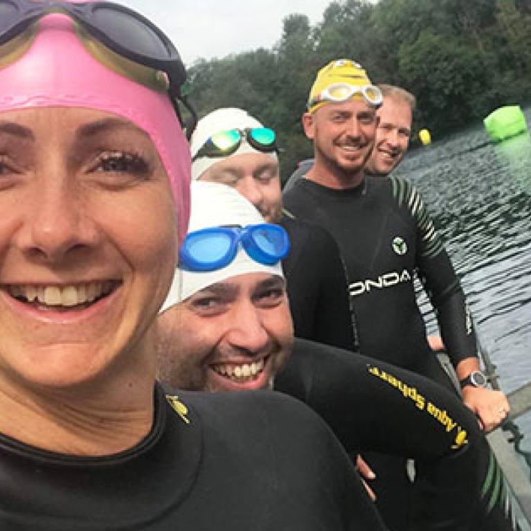 Swimmers wearing swimming caps and smiling