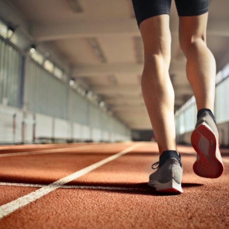 The legs of an athlete on an indoor running track in the afternoon.