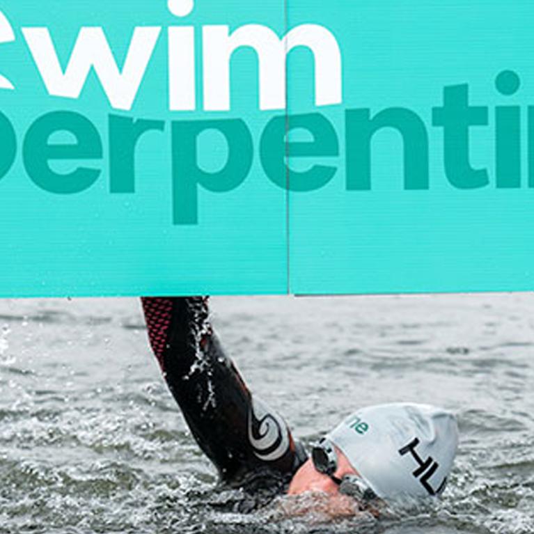 Someone swimming under a "swim serpentine" banner