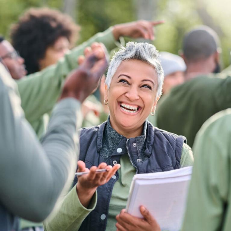 An excited woman at a running event smiling and holding a pen and books.