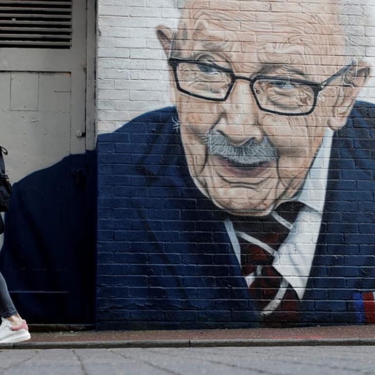 A woman walks past a new mural of British veteran and fundraiser Captain Tom Moore