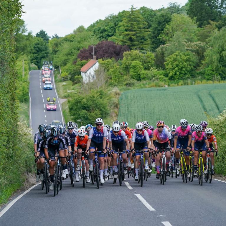 Pro riders cycle along a hilly country road