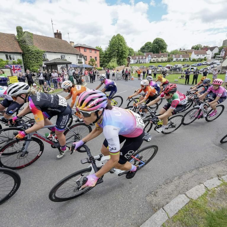 A group of elite cyclists passes through a village