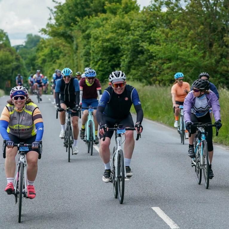 Smiling cyclists ride along a country road