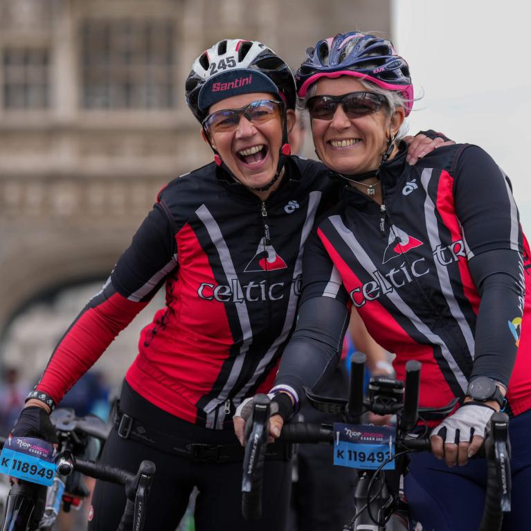 Two riders smile and hug at Tower Bridge