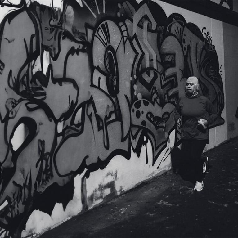 Local runner, Ruba Talukdar running. through an urban alley with graffiti on the walls