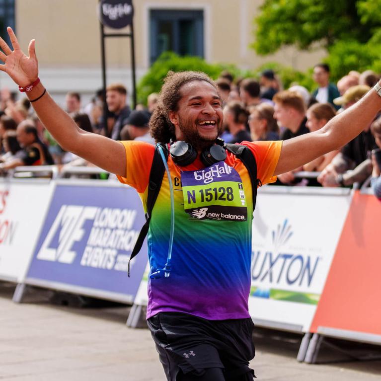 Man smiles with arms up as he runs The Big Half