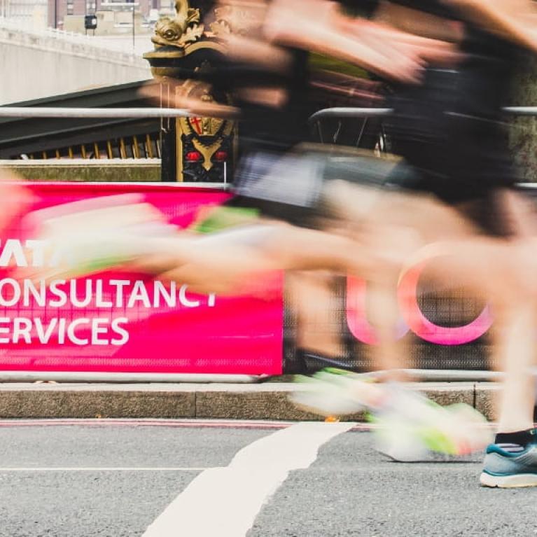 Runners run past some TCS branding