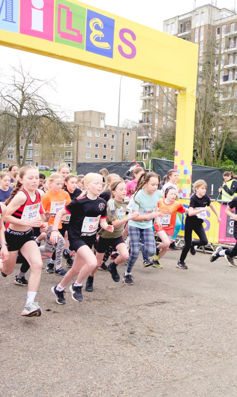 Multiple children running off the start line of the race